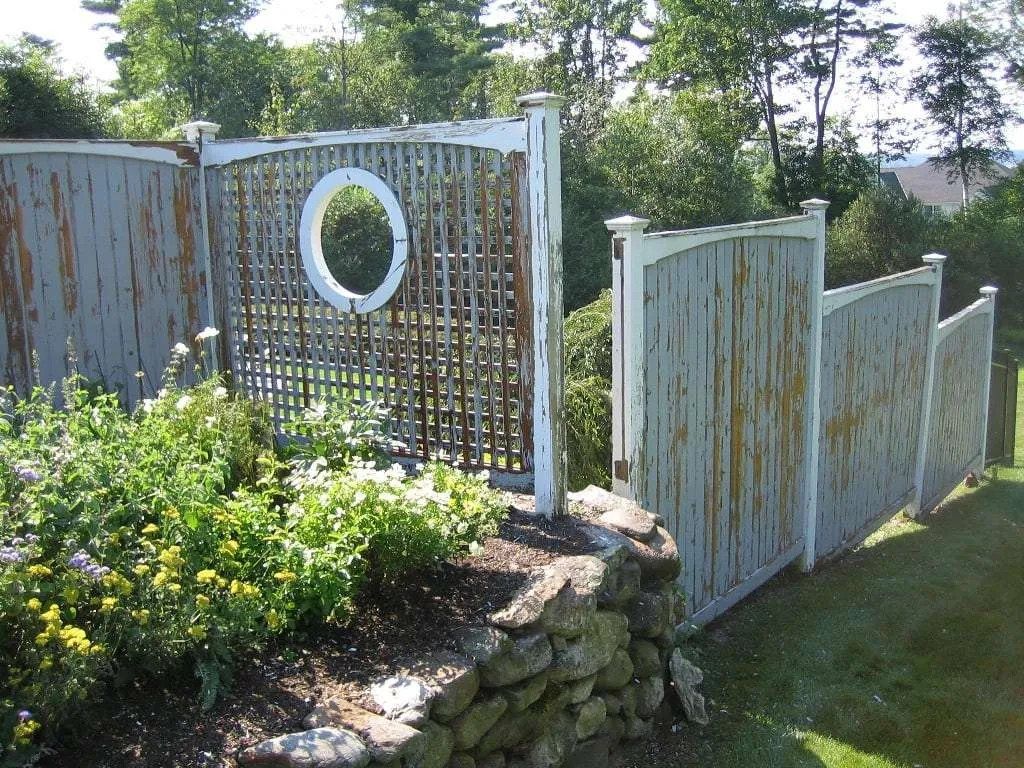 Light blue wooden privacy screens with a round lattice window, paint faded and peeling