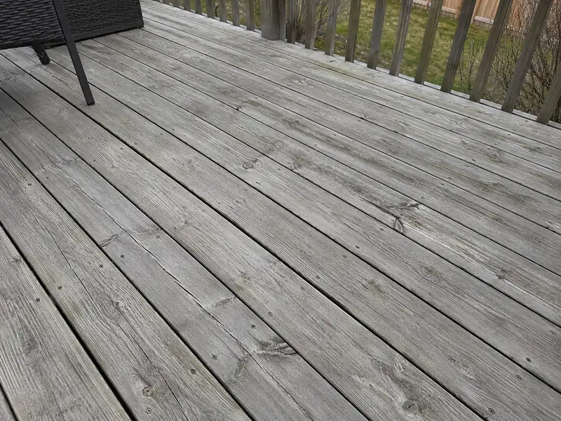 Grey, weathered deck boards with raised grain, small cracks and no finish left on them